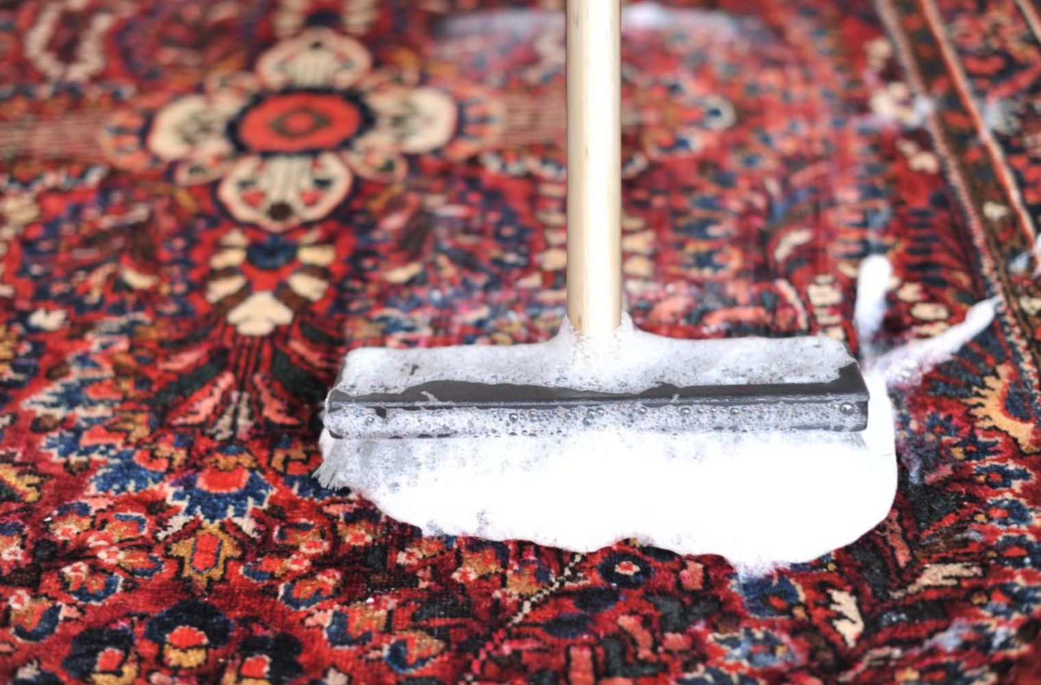 Scraping soapy water out of a rug at herbal washing facilities of Carpet Cellar